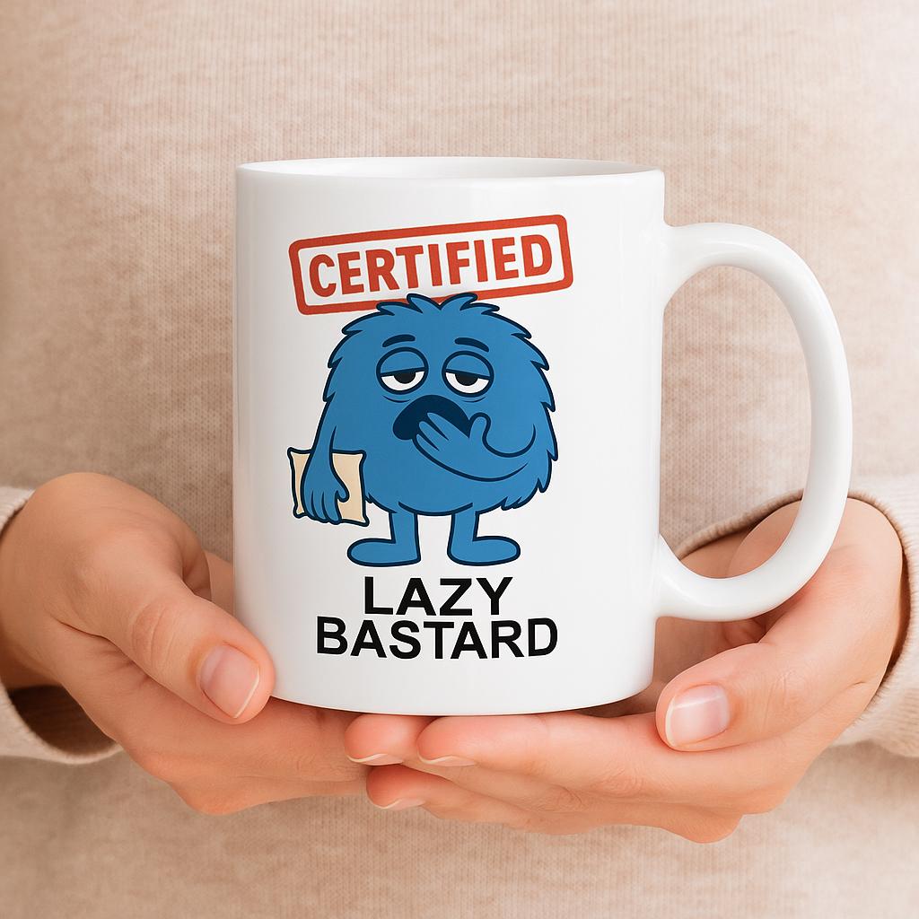 White ceramic coffee mug with a cartoon blue furry character holding a pillow, red ‘Certified’ stamp above, and text ‘Lazy Bastard’ below.