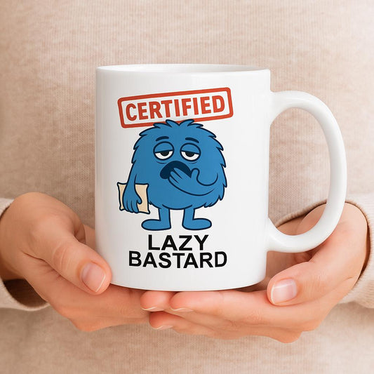 White ceramic coffee mug with a cartoon blue furry character holding a pillow, red ‘Certified’ stamp above, and text ‘Lazy Bastard’ below.