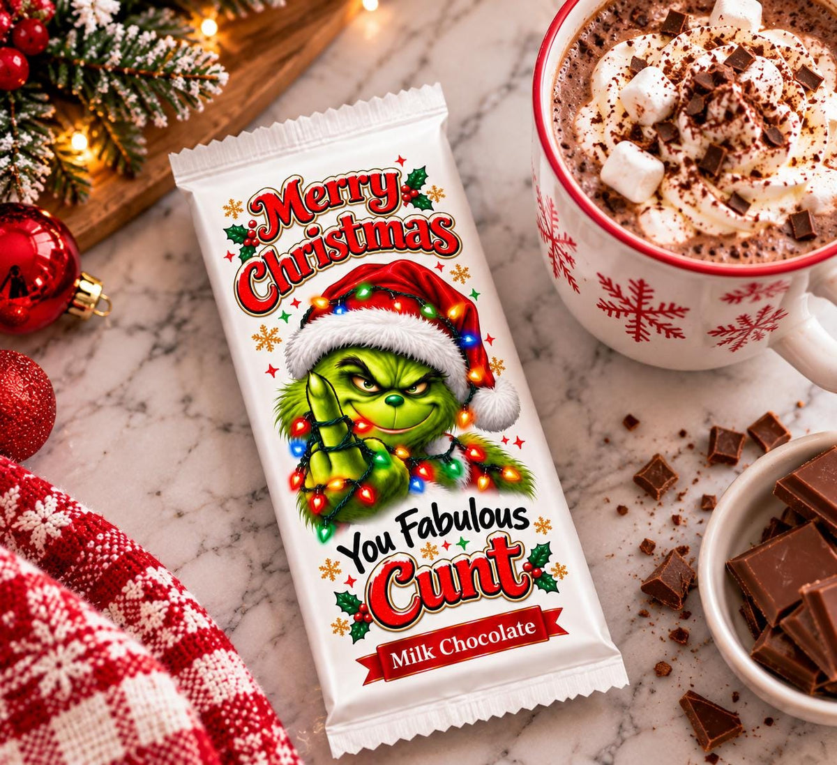 Funny Christmas milk chocolate bar with a rude Grinch wrapper beside hot chocolate on a marble surface.